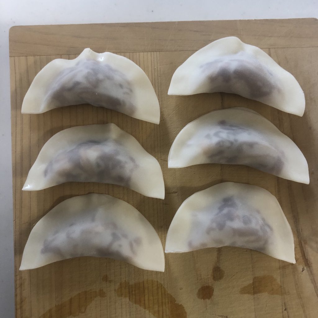餃子の皮に煮リンゴを包む様子